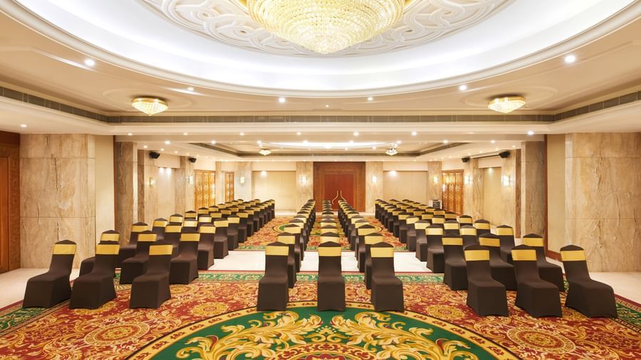 An image of a banquet hall with three columns of chairs and a huge chandelier light - Accord Puducherry